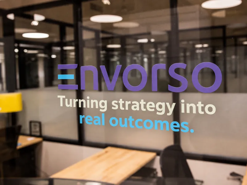 An AI-generated image of the Envorso logo and “Turning strategy into real outcomes.” on an office glass wall.